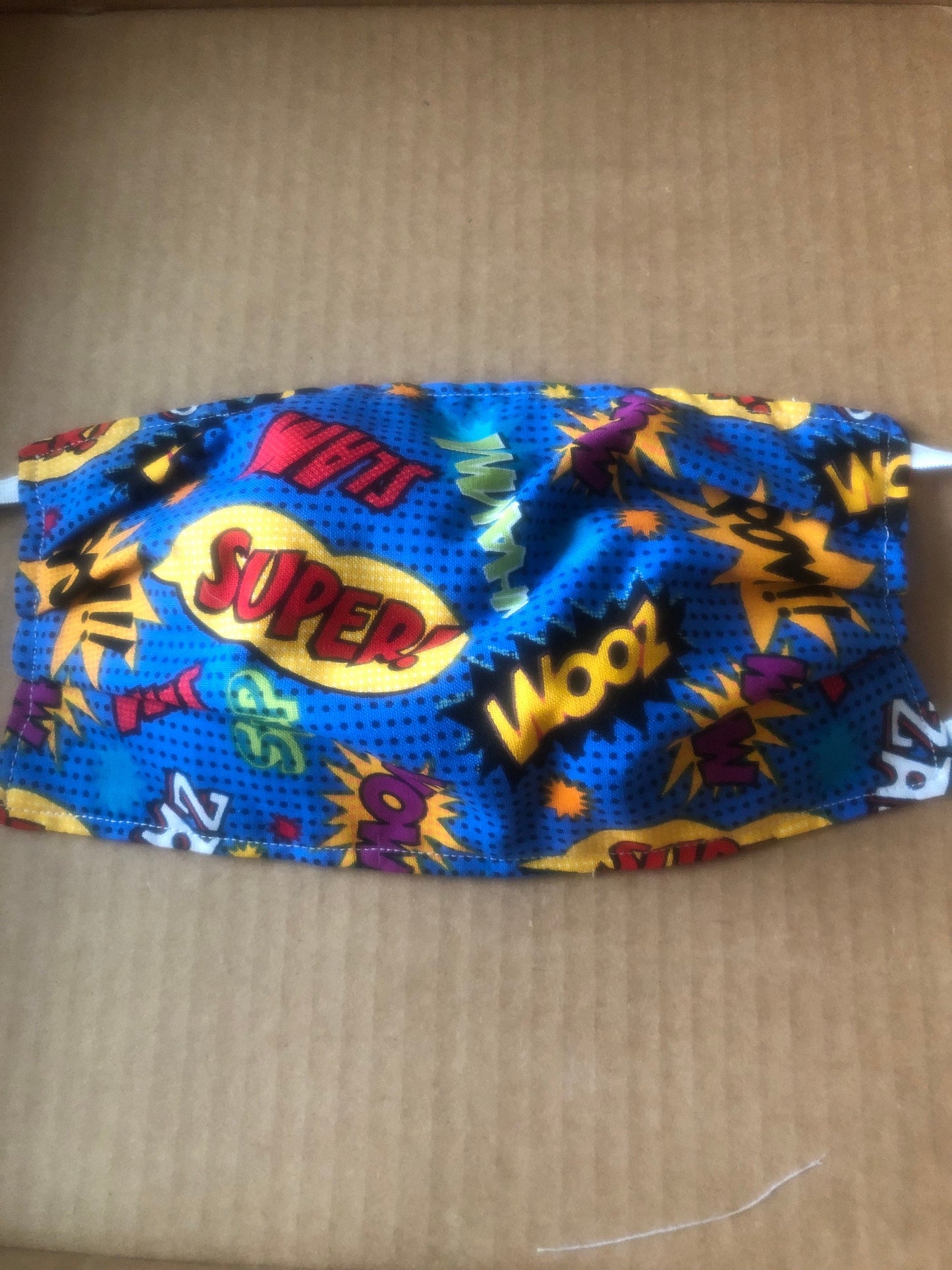 Fun super hero face mask with sayings like super, wow. Pow, etc.